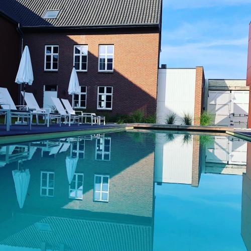a swimming pool with chairs and a building at Hof van Stayen in Sint-Truiden