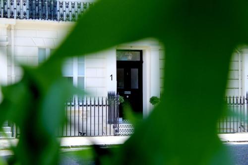 une maison blanche avec une porte noire et une clôture dans l'établissement 1 Craven Hill Gardens, à Londres