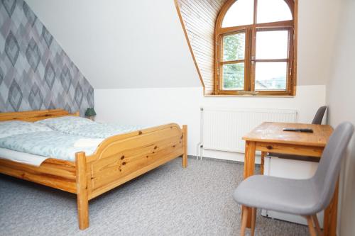 a bedroom with a bed and a desk and a chair at Penzion Terasa, bed & breakfast in Velké Losiny