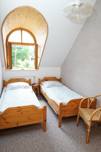 two beds in a room with a window and a chair at Penzion Terasa, bed & breakfast in Velké Losiny
