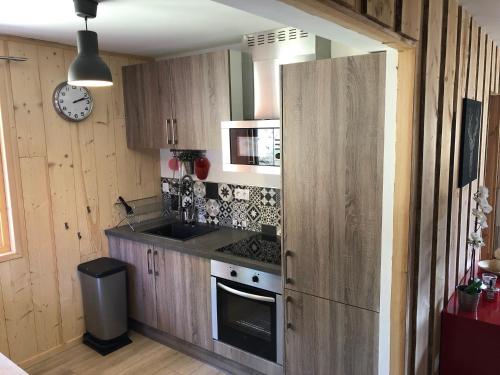 een keuken met houten kasten en een fornuis bij Vue Panoramique - 800m pistes Hohneck - Wifi - classé 3 étoiles in La Bresse