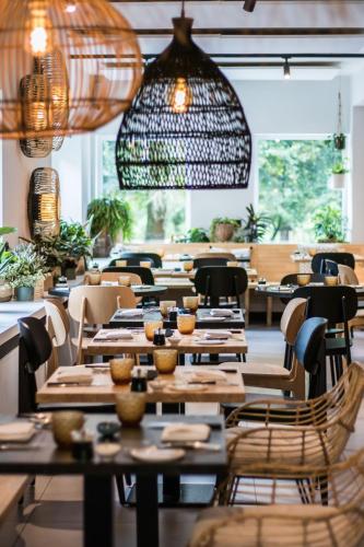 a restaurant with wooden tables and chairs and lights at Hotel & Apartments Bibois Leuven in Oud-Heverlee