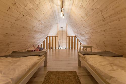 two beds in a large room with wooden walls at Ostoja Orżyny, Dom nr 1 - W stronę jeziora in Orzyny