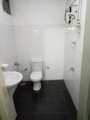 a white bathroom with a toilet and a sink at Pabasara hotel in Kiribathgoda