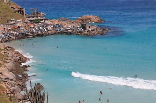 una playa con gente nadando en el agua en Massambaba Hostel, en Arraial do Cabo
