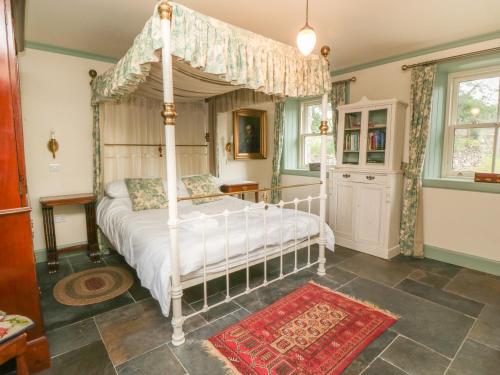 a bedroom with a canopy bed and a red rug at Faldarroch Farm in Newton Stewart