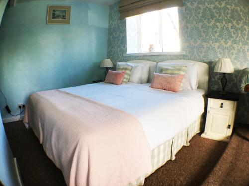 a bedroom with a large white bed with pink pillows at Hillside Bed and Breakfast in Crediton