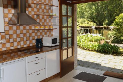 a kitchen with white cabinets and a microwave at Apartamentos Tarrio in Santillana del Mar