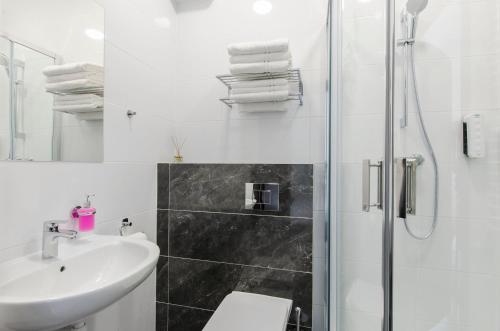 a white bathroom with a sink and a shower at Bema Rooms in Łódź
