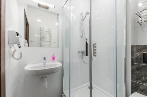 a white bathroom with a sink and a shower at Bema Rooms in Łódź