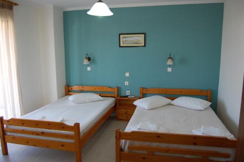 two beds in a room with blue walls at Giorgos Apartments Square in Nea Vrasna