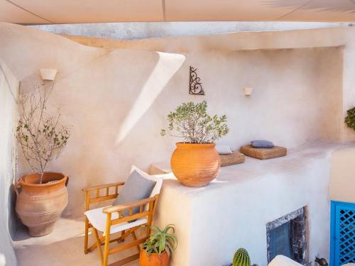 Habitación con plantas, silla y chimenea en Anemi House & Villas, en Oia