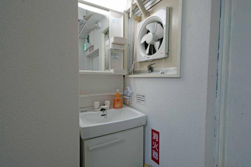 越谷市にあるタローズホステル南越谷の洗面台と鏡のあるバスルーム