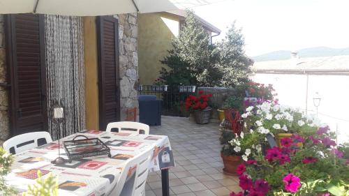 a white table with chairs and flowers on a patio at Casa Sa Hosta in Gavoi