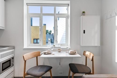 a kitchen with a white table and chairs and a window at Aalesund City Apartment in Ålesund