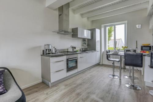 une cuisine avec des armoires blanches et des tabourets de bar dans l'établissement Kerelen, à Carantec
