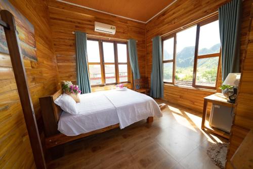 Diep Le Homestay في فونغ نها: غرفة نوم بسرير وملاءات بيضاء ونوافذ