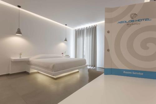 a white bedroom with a bed and a room service sign at Aeolos Resort in Mýkonos City