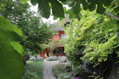 einen Garten mit einem roten Haus im Hintergrund in der Unterkunft CLOUD 7even in Müllheim