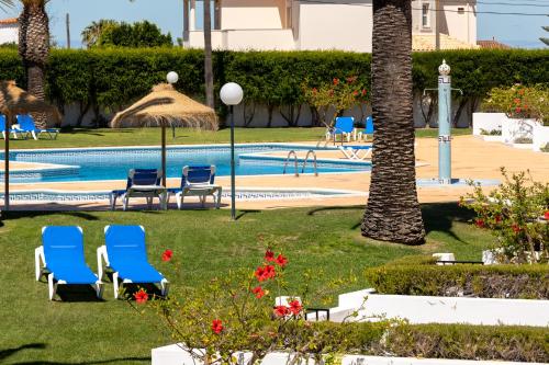 a resort with chairs and a swimming pool at Moradias Villas Joinal in Albufeira