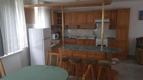 una cocina con armarios de madera y una barra con taburetes en Royal Apartman, en Vonyarcvashegy