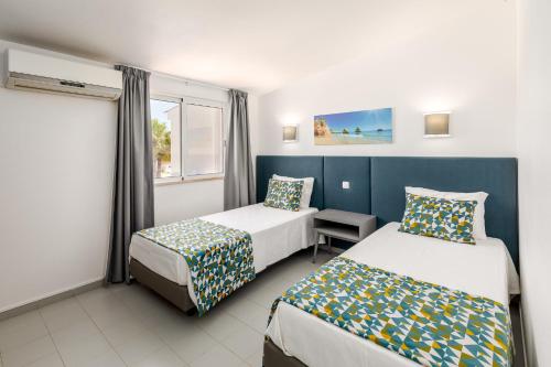 a hotel room with two beds and a window at Moradias Villas Joinal in Albufeira