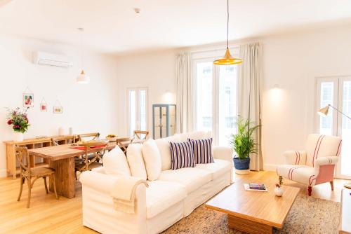a living room with a white couch and a table at Apartamentos Ferreiros by Heart of Funchal in Funchal
