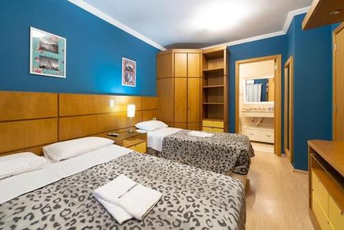 two beds in a room with blue walls at GRAMADO SOLAR REAL - 2 APTS de 2 quartos no mesmo prédio, cada um comporta até 7 pessoas - IDEAL PARA GRUPOS - central - IDEAL PARA ANDAR A PÉ, nesta plataforma desde janeiro de 2016, oferecemos CREDIBILIDADE - seu PET é bem-vindo - GARAGEM COBERTA in Gramado