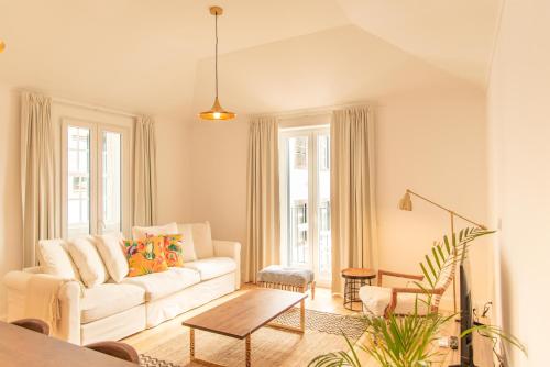 a living room with a white couch and a table at Apartamentos Ferreiros by Heart of Funchal in Funchal