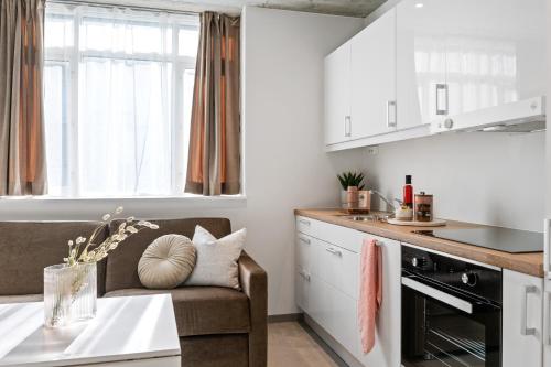 a kitchen with white cabinets and a couch and a table at Aalesund City Apartment in Ålesund