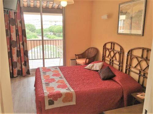 um quarto com uma cama com um cobertor vermelho e uma janela em Hotel Alhambra em Cap d'Agde
