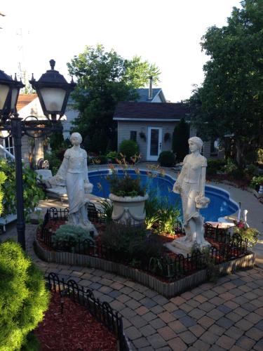 three statues in a garden next to a pool at Chez Danny in Montreal