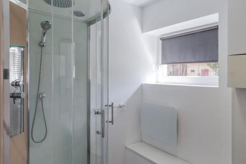 a white bathroom with a shower and a window at Les Jardins de Lo're'an in Holtzwihr