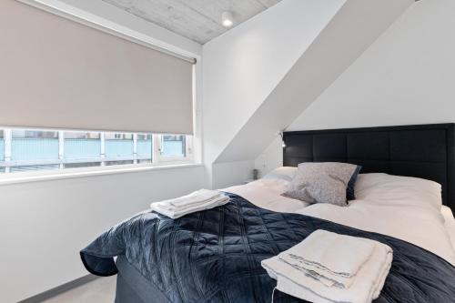 a bedroom with a bed with a black headboard and a window at Aalesund City Apartment in Ålesund