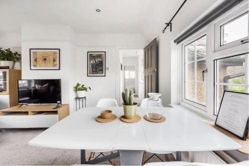 a white dining room with a white table and a tv at The Film Studio Appartement 5 min to Harry Potter in Leavesden Green