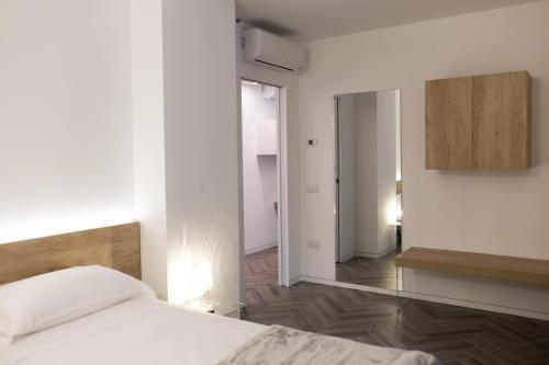 biała sypialnia z łóżkiem i lustrem w obiekcie Terrazze dei Tigli w mieście Riva del Garda