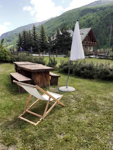 a chair and an umbrella next to a picnic table at Baita del Plan in Pragelato