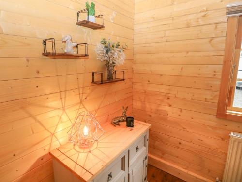 Bryn Derwen Lodge في بانغور: حمام بجدران خشبية وطاولة مع حوض