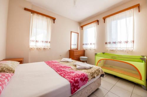 a bedroom with a bed with a green headboard and windows at Villa Gardenia in Dalyan