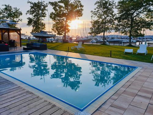 a swimming pool with the sun setting in the background at Butique Apartman in Balatonlelle