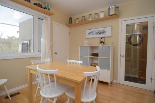 a dining room with a wooden table and white chairs at U of A Homestay, Trails & Whyte Ave in Edmonton