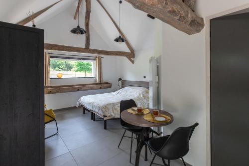 a bedroom with a table and chairs and a bed at La Pomme Pétillante in Maisnières
