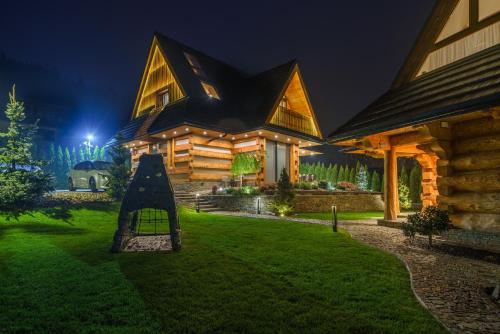 a log home at night with a playground in front at Luxury Chalet Wioska Jagny in Poronin
