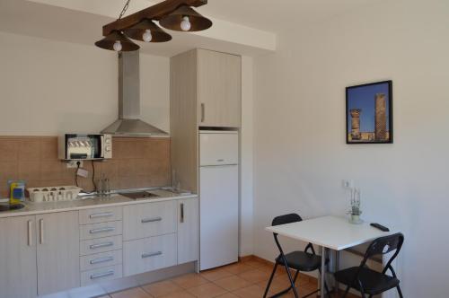 una cocina con armarios blancos y una mesa con sillas. en Rural Reillo Alojamientos Rurales en Reíllo