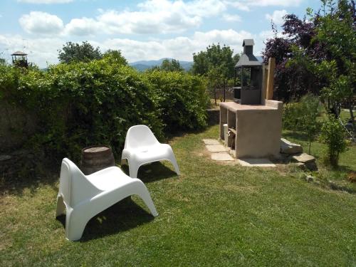 two white chairs sitting in the grass next to a stove at A Boira Rural in Osia
