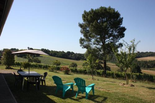 a table with chairs and an umbrella in the grass at A POUTET in Labarthète