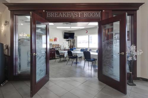 un restaurante con sala de desayunos con mesa y sillas en Ramada by Wyndham Nisku Edmonton Airport, en Nisku