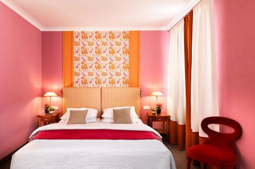 a bedroom with a bed with pink walls and a red chair at Hotel Goliath am Dom in Regensburg