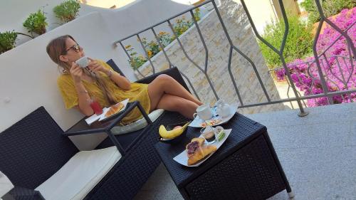 Una donna è seduta su un balcone a mangiare. di Maison Margherita a Santa Teresa di Gallura