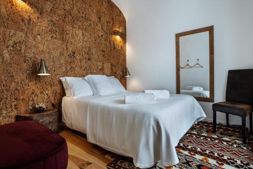 a bedroom with a large white bed and a mirror at Alfar Story - Évora House in Évora